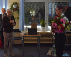 Dwóch Panów stoi oraz Pani, która trzyma kwiaty