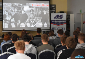 Młodzież siedzi, a w tle widać slajd z prezentacji