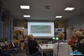 Osoby siedzące przy stole patrzą na slajd skąd biorą się choroby