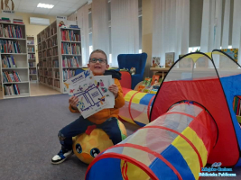 Chłopiec siedzi na piłce a w dłoniach trzyma dyplom