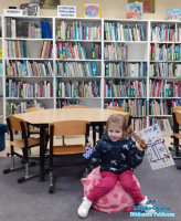 Dziewczynka siedzi na piłce i trzyma w dłoniach dyplom