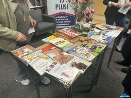 Książki leżą na stoliku a obok stoją osoby