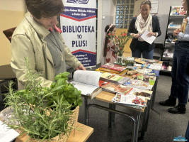 Trzy Panie stoją, jedna ogląda książkę przy stoliku