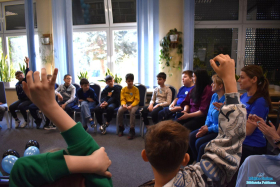 Dzieci siedzą w kółku i zgłaszają się do wypowiedzi