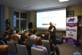 Pan pokazuje książkę, a młodzież siedzi