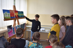 Chłopiec stoi przy sztalugach a obok niego dzieci