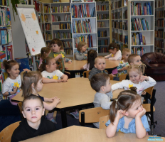 Dzieci podczas spotkania siedzą przy stolikach