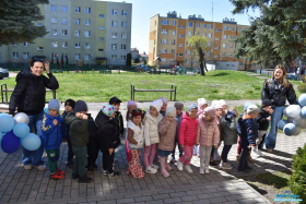 Dzieci stoją przed budynkiem i pozują do zdjęcia
