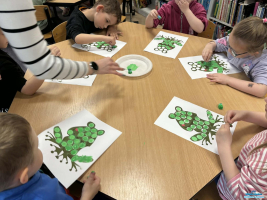 Dzieci wykonują prace plastyczne siedząc przy stoliku