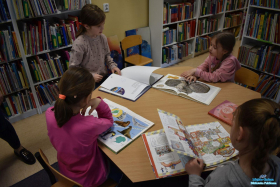 Cztery dziewczynki przy stoliku oglądają książki