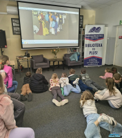 Dzieci leżą na podłodze i oglądają bajkę