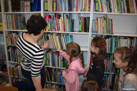 Pani i trzy dziewczynki szukają książek na półkach