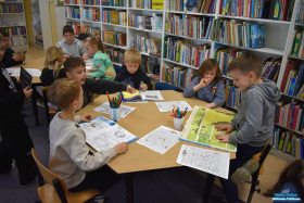 dzieci siedzą przy dwóch stolikach oraz oglądają książki