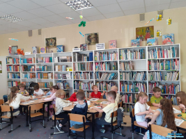 Dzieci siedzą przy stolikach i wykonują prace plastyczne