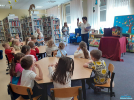 Pani stoi przed dziećmi i pokazuje im kartę biblioteczną