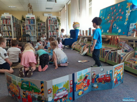 Dzieci siedzą na podłodze a obok stoi rozłożona książka