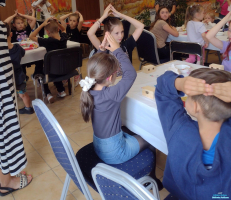Dzieci siedzące i trzymające ręce splecione nad głowai
