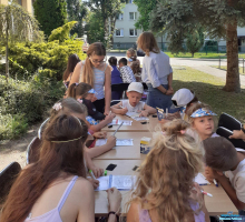 Dzieci siedzą przy stoliku i rysują w notesikach