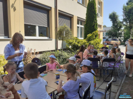 Grupa dzieci siedzi przy stolikach