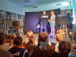 CHłopiec stoi na stołeczku a obok Pan trzyma kartkę