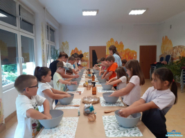 Dzieci stoją przy stole i trzymają recę w miseczkach