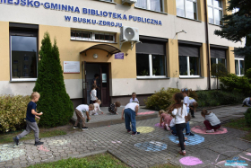 Dzieci kolorują chodnik przed budynkiem