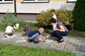 Pani rysuje z dziećmi kredą na chodniku