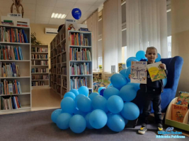 Chłopiec stoi na tle balonów