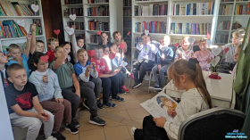 Dzieci siedzą i trzymają w dłoniach serduszka na patyczkach