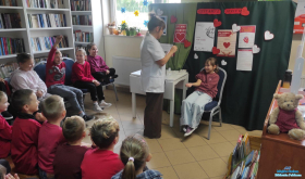 Pani stoi a obok siedzi dziewczynka