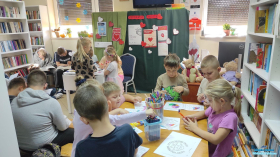 dzieci siedzą przy stolikach i wykonują prace plastyczne