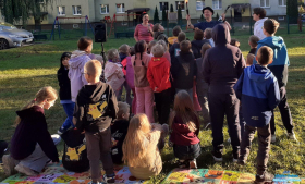 dzieci stoją koło osoby dorosłej która odpala pochodnie do żąglerki