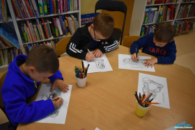 trzech chłopców koloruje kolorowanki