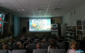 Dzieci oglądają film siedząc na krzesełkach