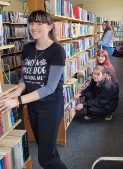 dziewczyny stoją przy regale z książkami i pozują do zdjęcia