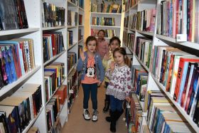Cztery dziewczynki pozują do zdjęcia wśród półek z książkami