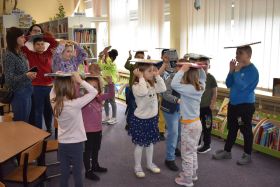 Dzieci stoją w grupie i trzymają książki na głowie