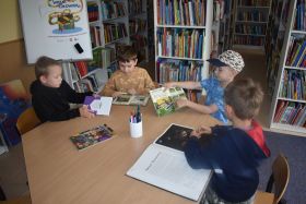 Czterech chłopców przy stoliku ogląda książki