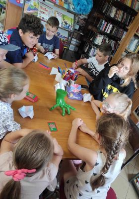 Dzieci siedzą przy stoliku z grami planszowymi