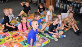 Grupa dzieci siedzi na kolorowych matach
