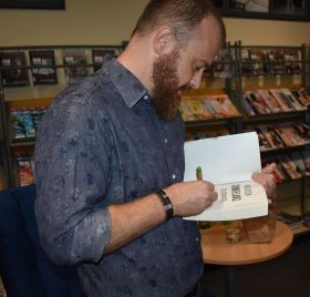 Wojciech Chmielarz składa swój autograf w książce