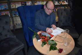 Grzegorz Rak podpisuje egzemplarz książki