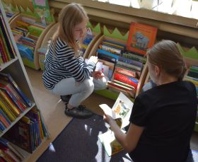 Dziewczynki przeglądają księgozbiór