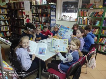 Dzieci siedzą przy stoliku i prezentują książki