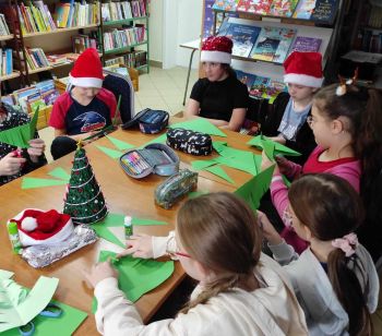 Dzieci w czapkach Mikołaja siedzą przy stoliku