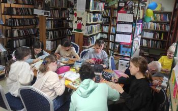 Dzieci siedzą przy stoliku w bibliotece
